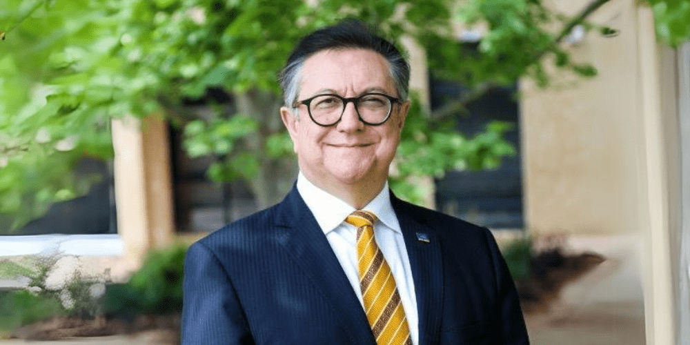 Professional caucasian man wearing glasses smiles at camera in outdoor setting